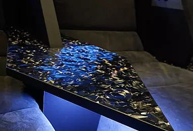 Detailaufnahme eines individuell gestalteten Tisches zwischen gepolsterten Kinositzen im Filmpalast Lüdenscheid.