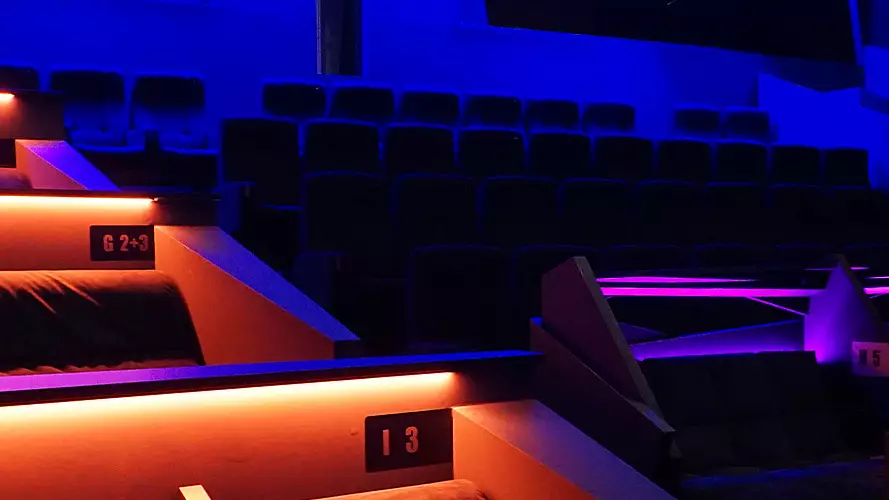 Kinosaal im Filmpalast Lüdenscheid mit unterschiedlichen Sitz- und Loungebereichen sowie farbigem Lichtkonzept.